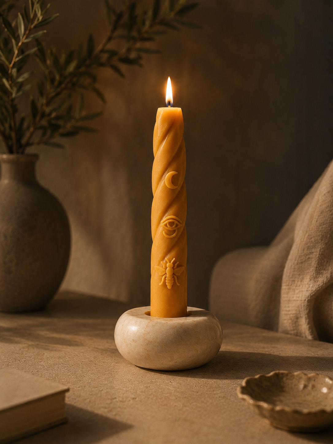 `Burning Moon ISIS beeswax candle with crescent moon, Eye of Horus and bee symbols, set in a natural alabaster holder in a warm, minimalist interior.`
